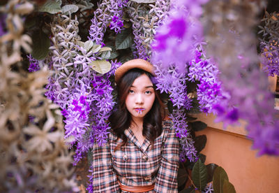Portrait of young woman standing by plants