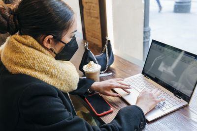 Teenage girl e-learning through laptop in cafe