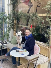 Portrait of man with dog sitting at restaurant