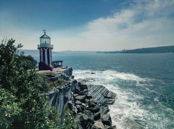 Lighthouse by sea against sky