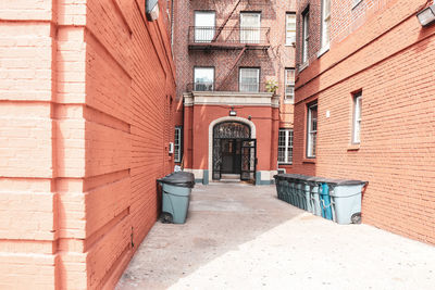 Entry door of orange brick old buildings with fire stairs, and garbage cans bronx, nyc