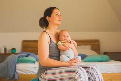 Portrait of young woman using mobile phone while lying on bed at home