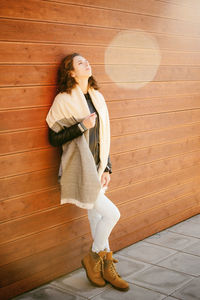 Young woman with eyes closed while standing against wall