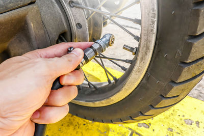 Cropped hand of man filling air in motorcycle tire