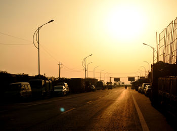 Cars on street in city against sky during sunset