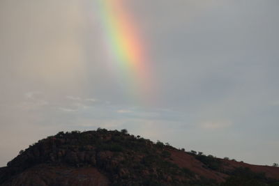 Low angle view of rainbow over mountain against sky