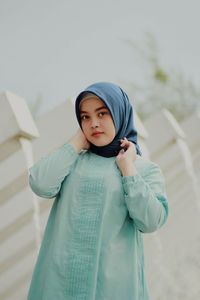 Portrait of young woman standing against wall