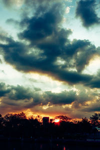 Low angle view of silhouette trees against dramatic sky