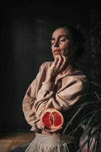 Young woman looking away against black background