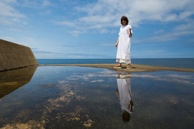 Rear view of man standing in sea against sky