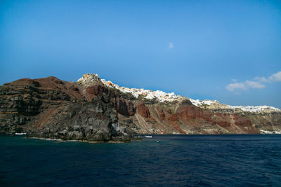 Scenic view of sea and mountains against clear blue sky