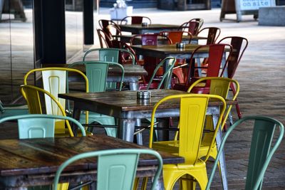 Empty chairs and tables at sidewalk cafe