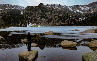 Man standing on rock by snow covered mountains