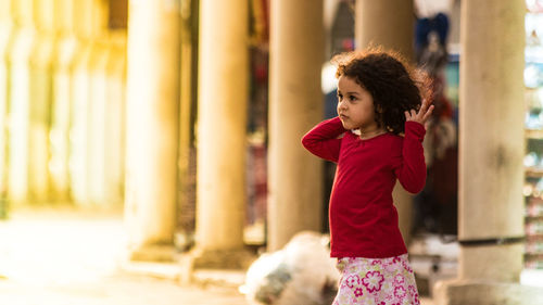 Girl looking away while standing against blurred background