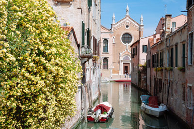 Boats in canal amidst buildings in city