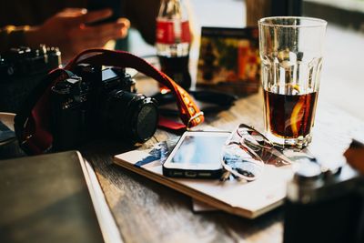High angle view of mobile phone with camera and drink on table