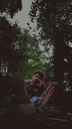 Midsection of woman sitting on land against trees