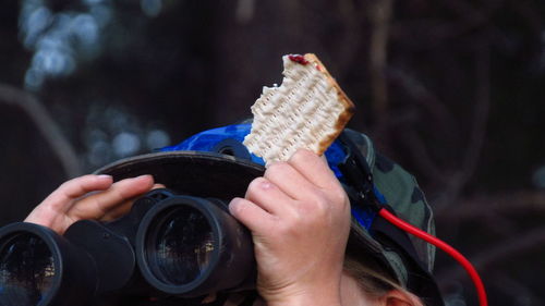 Close-up of hand holding binoculars and matzo.