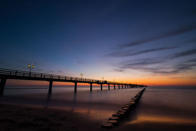 Pier over sea against sky during sunset