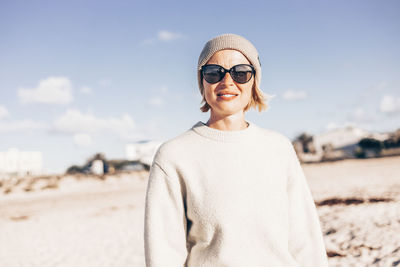 Portrait of young woman wearing sunglasses standing at beach