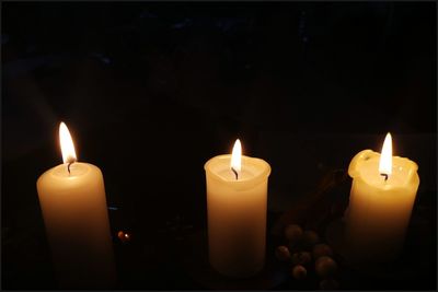 Close-up of lit candles in darkroom