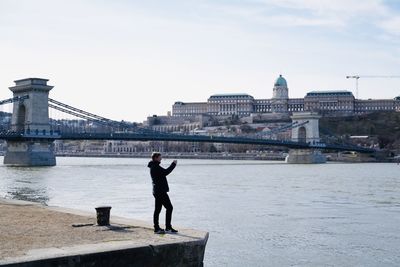 Rear view of woman walking on bridge against sky