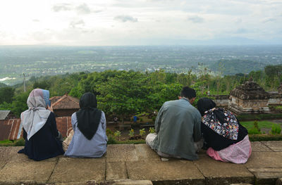 Rear view of people looking at temple against sky