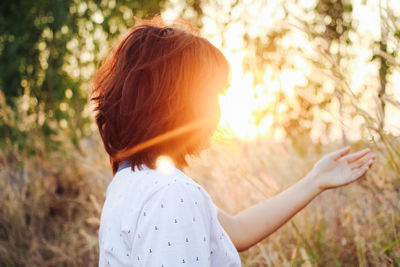 Rear view of woman standing on field in forest