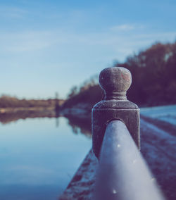 Close-up of old metal against lake