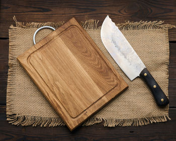 Large kitchen knife on an empty wooden cutting board, top view