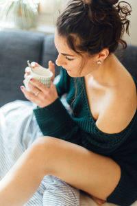 Close-up of woman having coffee while sitting on bed at home