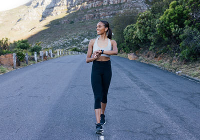 Full length of young woman exercising on road