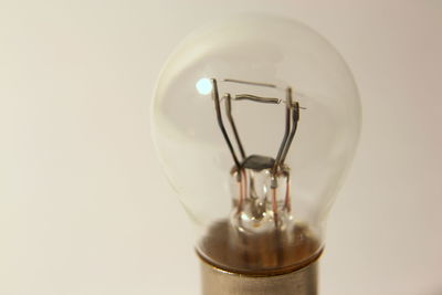 Close-up of illuminated light bulb against white background