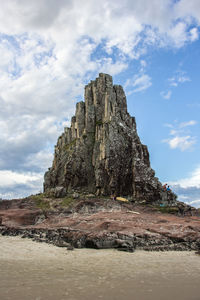 Rock formations on landscape against cloudy sky