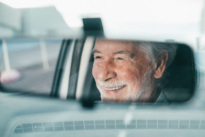 Reflection of senior man seen through rear view mirror