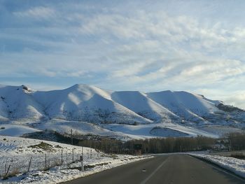 Road by mountains against sky during winter