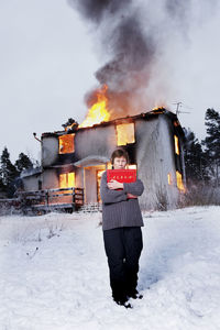 Rescued senior woman in front of burning house holding photo album