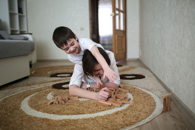 Beautiful brunette mom playing with kid boy on the floor in wooden designer, casual lifestyle 