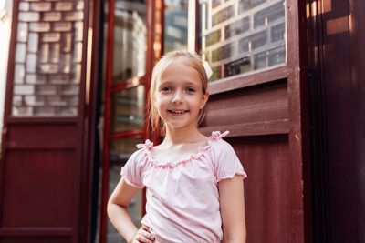 Portrait of young woman standing against building