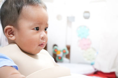 A happy asian baby boy sitting and wating some pap pudding by mom with spoon.