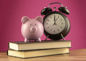 Stack of books on table against pink background