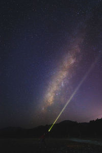 Mid adult man with flashlight against star field against sky at night