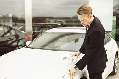 Side view of man examining car outside showroom