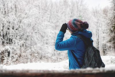Woman photographing on field during winter