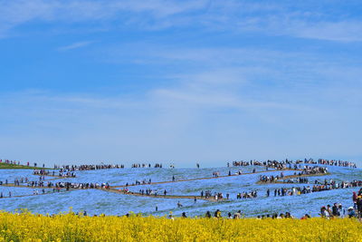 Group of people on landscape against blue sky