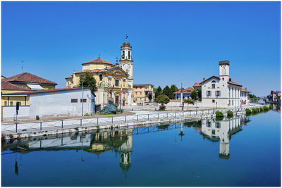 Reflection of building in water against clear blue sky
