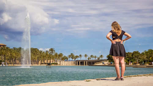 Rear view of woman looking at fountain against sky