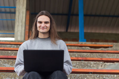 Young woman using mobile phone while sitting outdoors