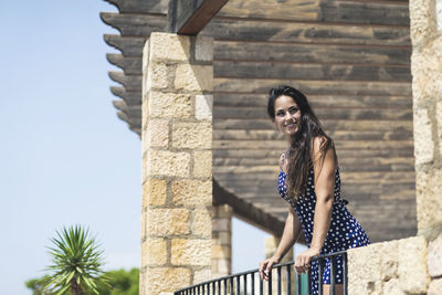 Smiling young woman standing by railing