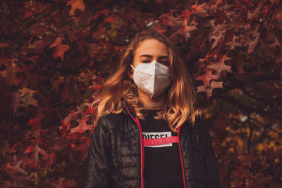 Portrait of young woman standing with autumn leaves